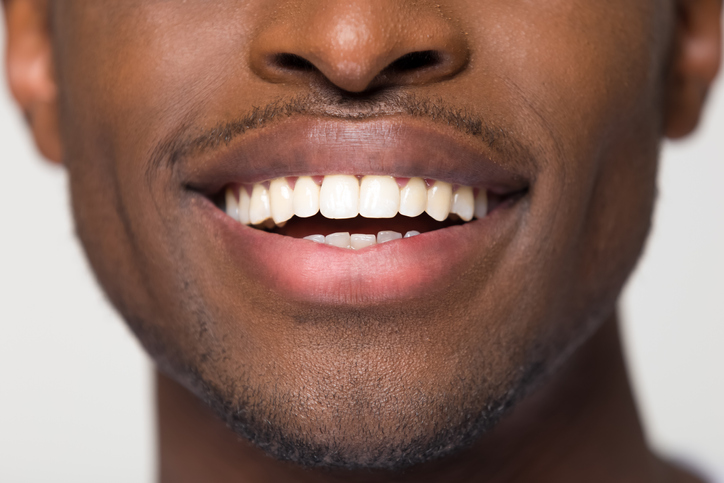 Close up of young man smiling, focus on mouth and teeth