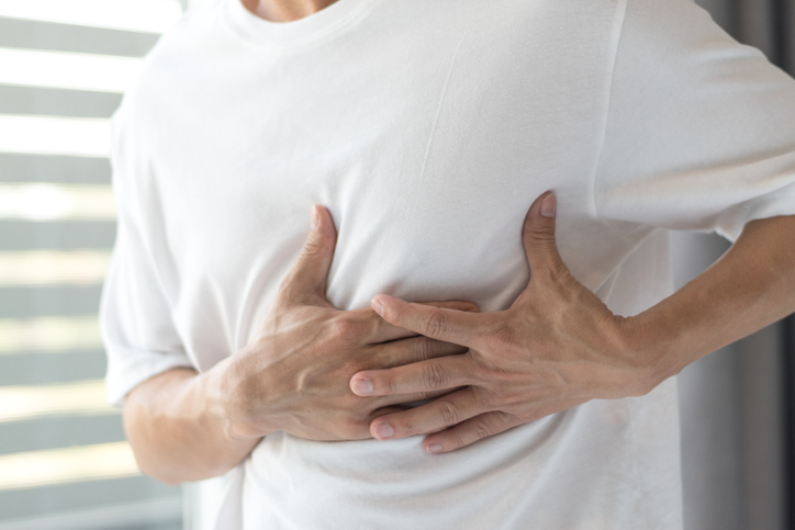 Man in white t-shirt with his hands on his chest, feeling his ribs