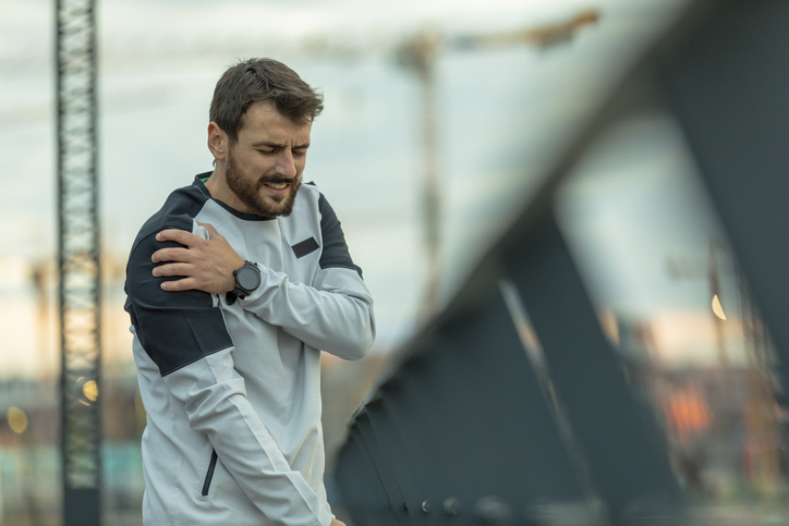 Man holding his shoulder in pain while out for a run