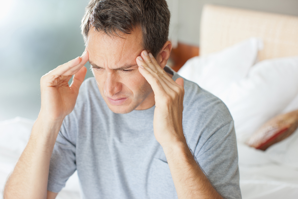 Man sitting on bed with hands on the side of his head, headache (credit - Paul Bradbury)