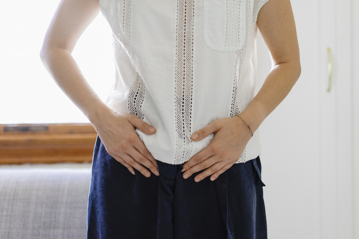 Young adult woman with hands on her pelvis 