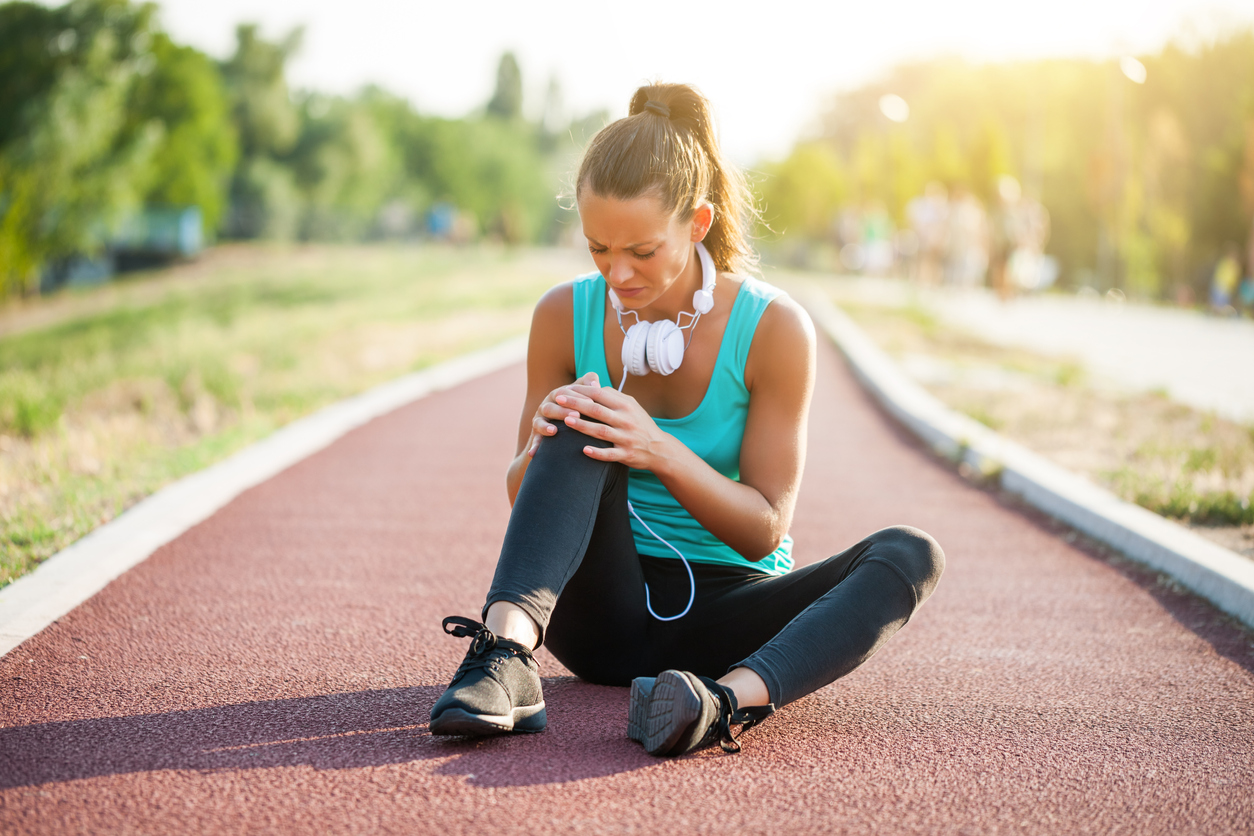 young-woman-feeling-her-knee-while-on-a-running-track-wearing-sports-clothes